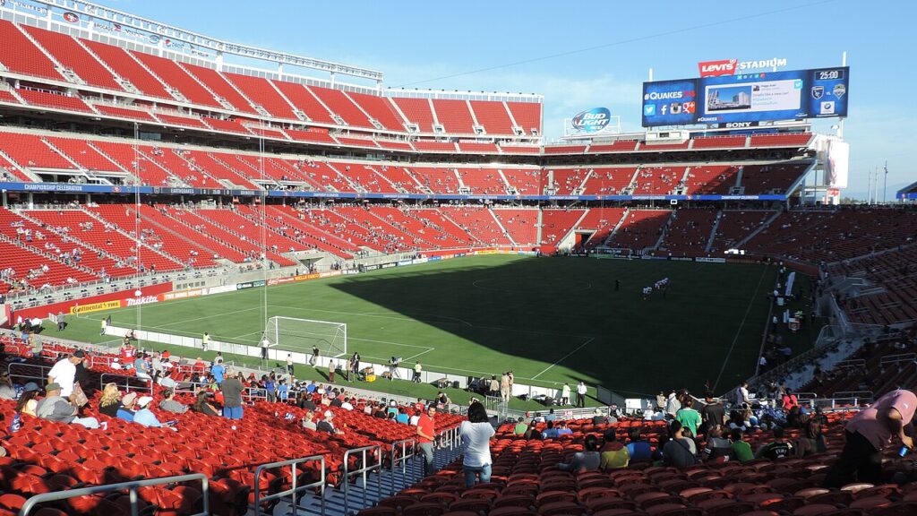 Sunlit soccer stadium with red seats